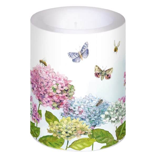 Vela cilíndrica con diseño floral con hortensias rosas, azules y amarillas y mariposas.