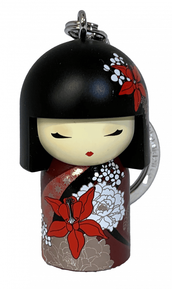 Llavero que presenta una muñeca con un corte de pelo bob negro, un vestido floral rojo y blanco y ojos cerrados.