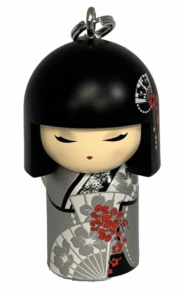 Un pequeño llavero de muñeca kokeshi con cabello negro, vistiendo un kimono gris decorado con flores rojas y negras.