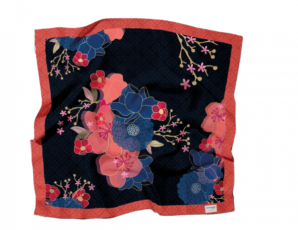 Un cuadrado de tela con fondo azul marino, adornado con grandes motivos florales rosas y azules, rodeado por un borde rojo con un patrón sutil.