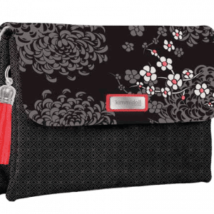 Un bolso de mano negro con estampado floral y detalles en rojo, que presenta una borla roja en el lateral.