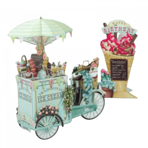El 3D014 CARRITO DE HELADOS, adornado con flores y un paraguas, se encuentra junto a un cartel de cumpleaños gigante con forma de cucurucho de helado.