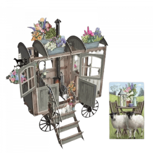 El 3D020 CABAÑA DEL PASTOR presenta un carro rústico adornado con flores, ovejas pastando cerca y una pequeña mesa exterior coronada con un arreglo floral.