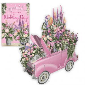 Un coche de boda 3D030 COCHE DE BODA ROSA-rosa lleno de flores de colores, emparejado con una tarjeta floral "Felicidades en el día de tu boda" de fondo.
