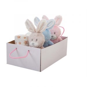 Una caja blanca con asas rosas que contiene un conejito de peluche azul, un conejito de peluche rosa y una manta blanca enrollada con estrellas doradas.